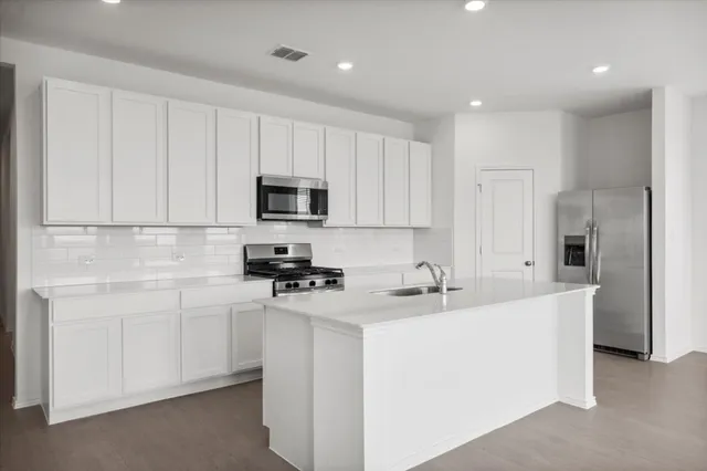 a kitchen with white cabinets and stainless steel appliances