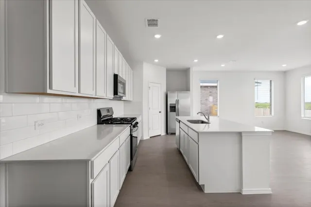 a kitchen with stainless steel appliances kitchen island granite countertop a stove and a refrigerator