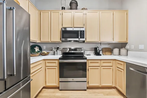 a kitchen with stainless steel appliances granite countertop a stove a sink and a refrigerator with white cabinets