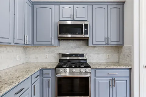 a kitchen with granite countertop white cabinets and stainless steel appliances