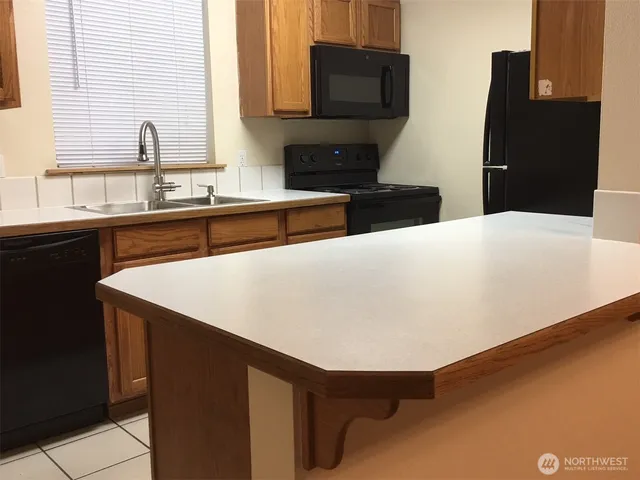 a kitchen with stainless steel appliances a sink a stove a refrigerator a counter top space and cabinets