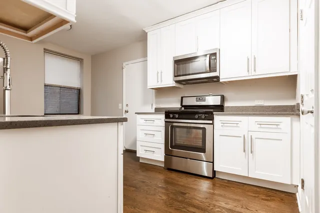 a kitchen with stainless steel appliances white cabinets and a stove top oven