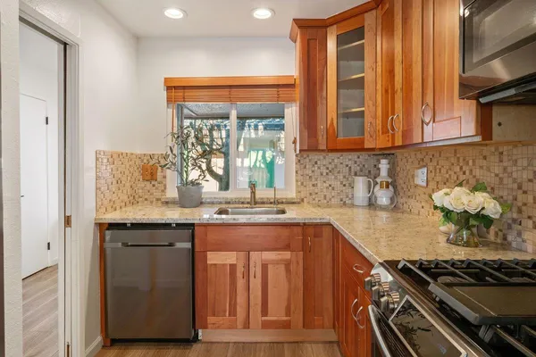 a kitchen with granite countertop wooden cabinets and a stove top oven
