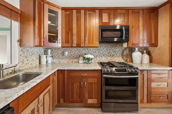 a kitchen with granite countertop a stove sink and microwave