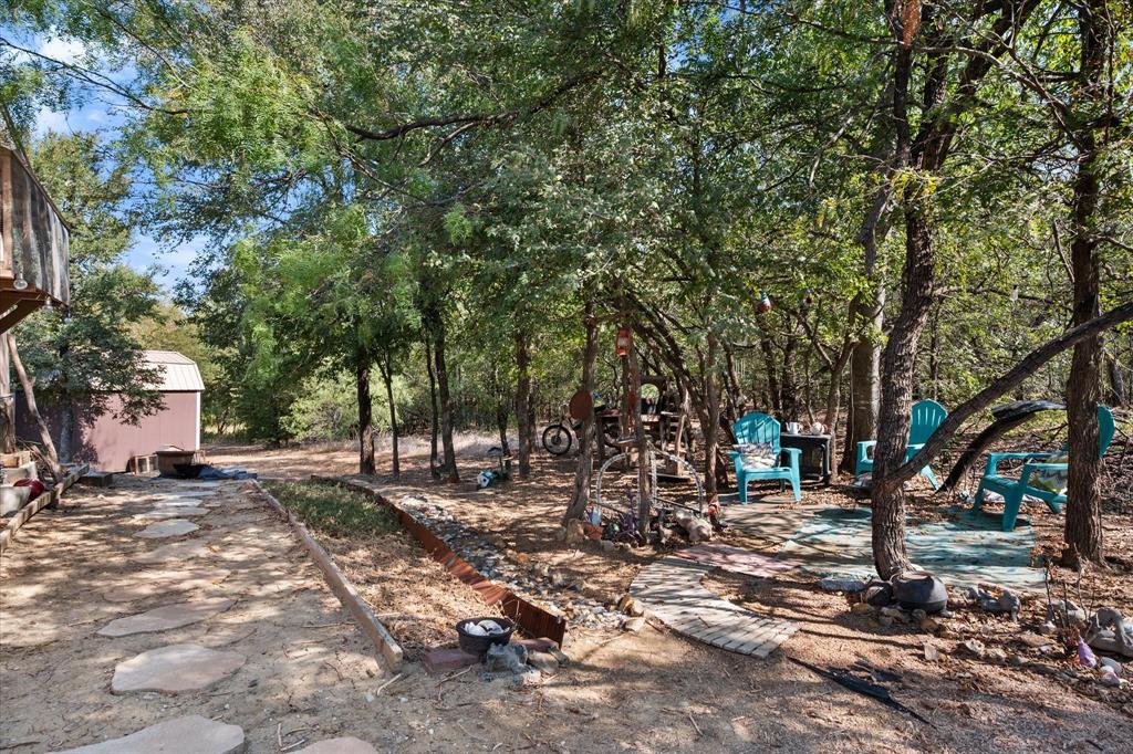 309 Southeast County Road Corsicana, TX 75109 - Photo 23 of 27 Wooded lot featuring mature trees, a stepping stone walkway, and a storage shed