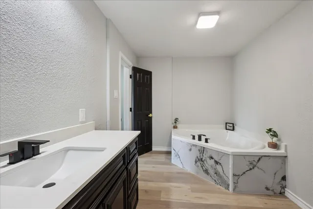a spacious bathroom with a tub sink and mirror