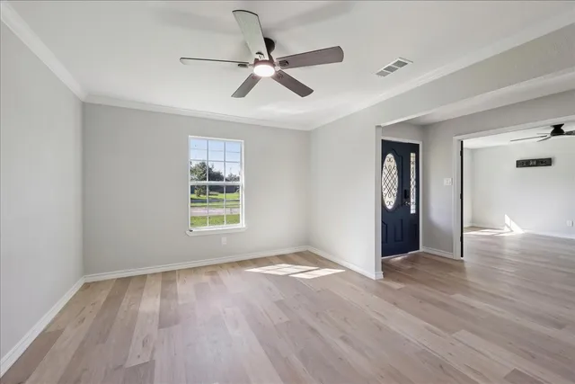 a view of an empty room with wooden floor and a window