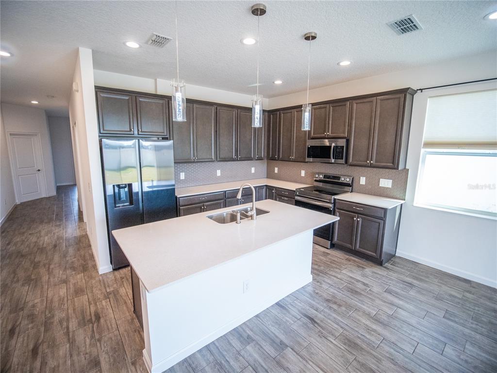 1257 Hendon Loop Davenport, FL 33837 - Photo 3 of 16 a large kitchen with stainless steel appliances granite countertop a stove a sink and a refrigerator