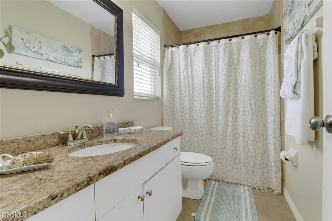 2223 Southwest 16th Terrace Cape Coral, FL 33991 - Photo 8 of 11 a bathroom with a granite countertop sink a toilet and a shower curtain
