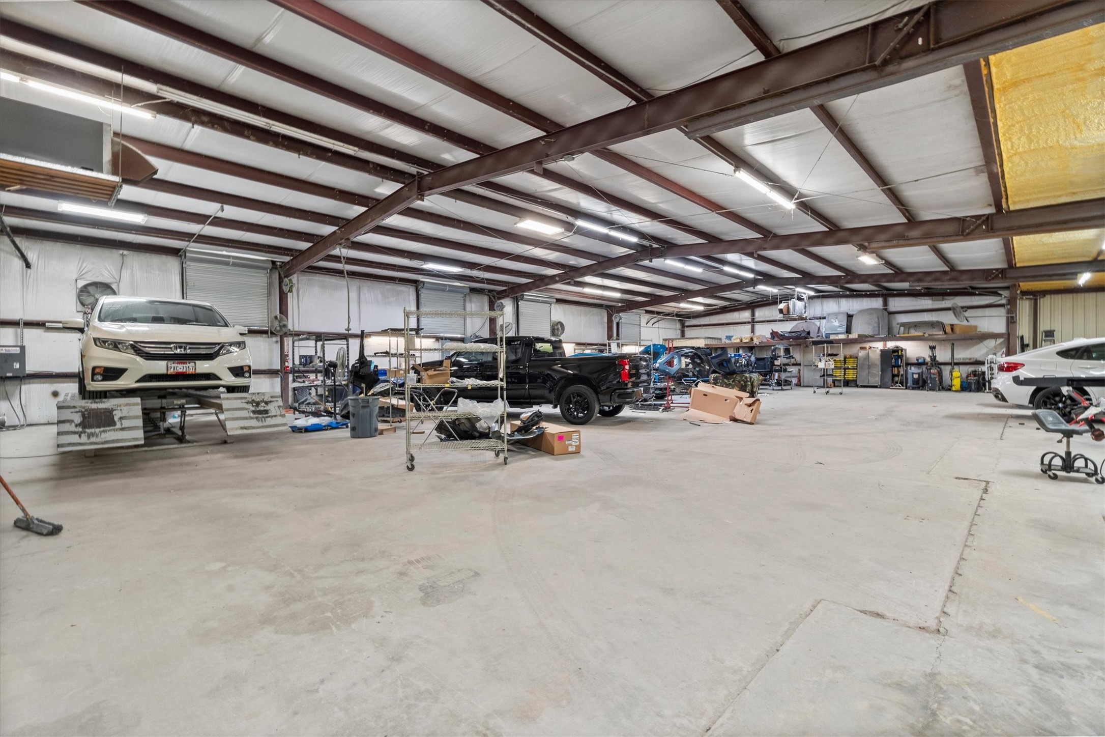 11066 Sh 242 Conroe, TX 77385 - Photo 20 of 21 This photo shows a spacious, well-lit garage or workshop area with multiple vehicles and ample storage space, ideal for automotive work or large-scale projects.