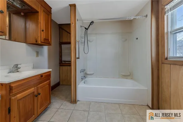 a bathroom with a tub sink shower and mirror