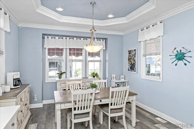 a dining room with wooden floor a chandelier a wooden table and chairs