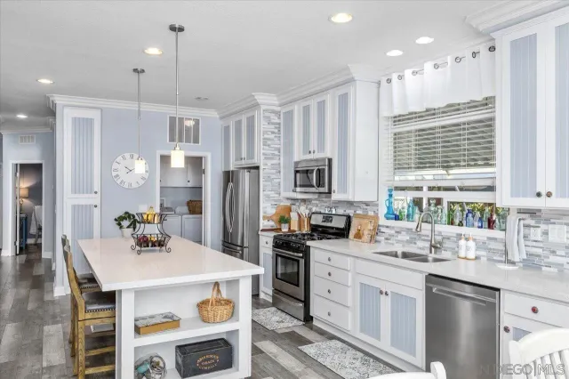 a kitchen with stainless steel appliances granite countertop a sink a stove a refrigerator cabinets and chairs