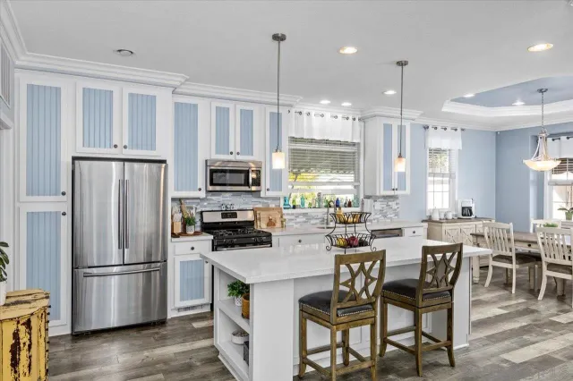 a kitchen with stainless steel appliances a dining table chairs stove refrigerator and cabinets