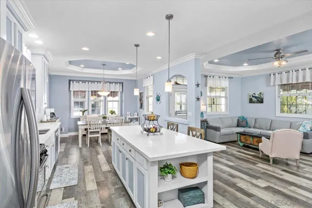 a view of a dining room and livingroom with furniture wooden floor a rug a flat screen tv a rug and a chandelier