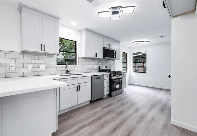 a kitchen with stainless steel appliances a sink a stove a microwave a sink a refrigerator and cabinets