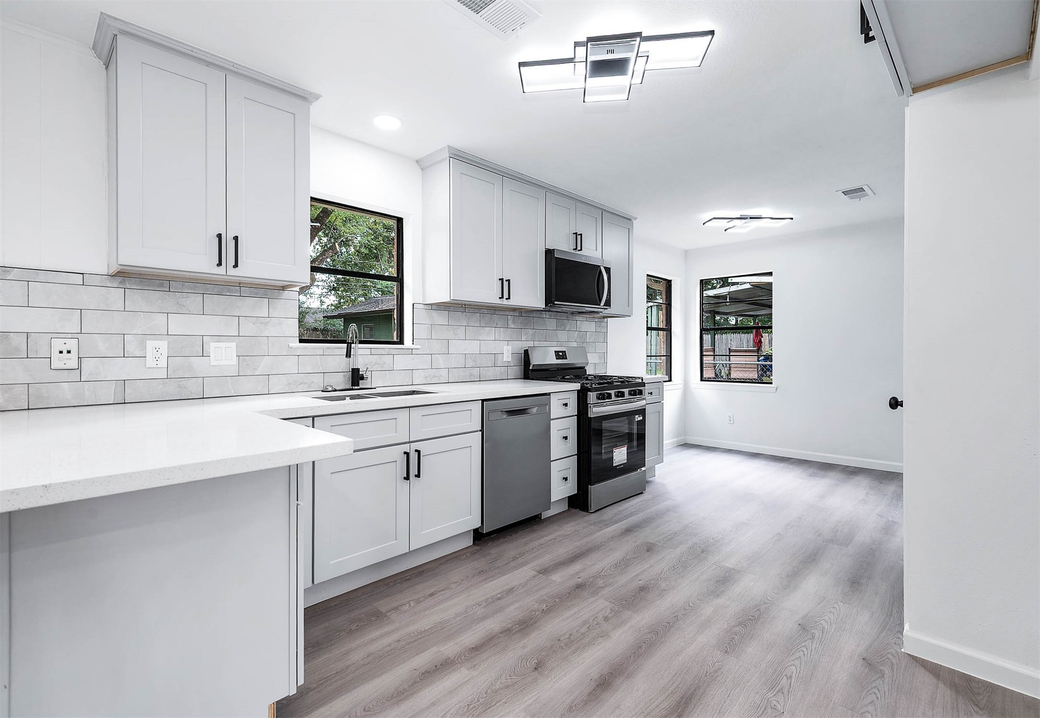 a kitchen with stainless steel appliances a sink a stove a microwave a sink a refrigerator and cabinets