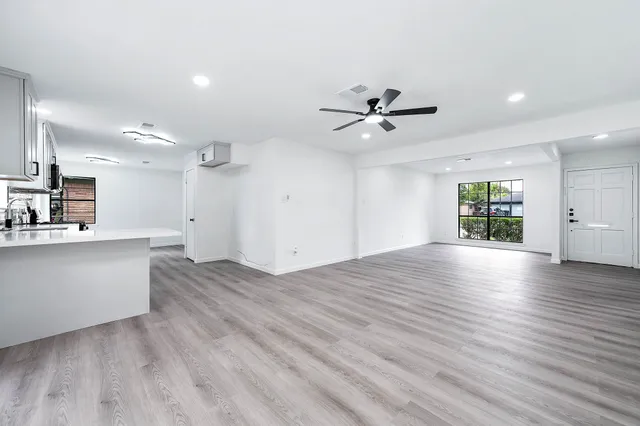 a view of an empty room with window and wooden floor