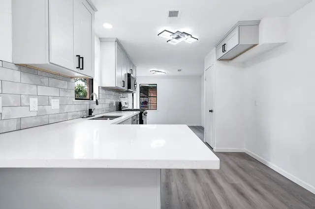 a large white kitchen with wooden floor