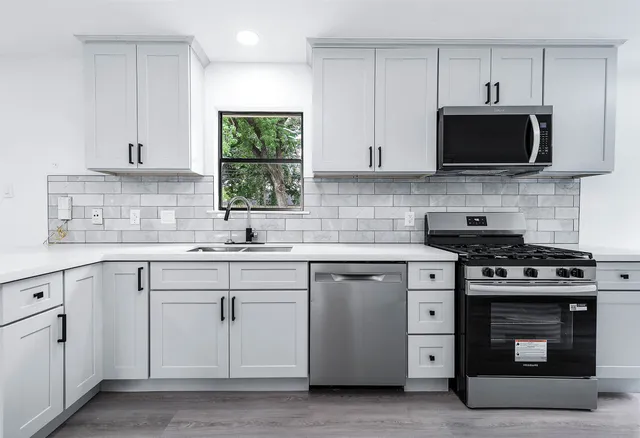 a kitchen with white cabinets and stainless steel appliances
