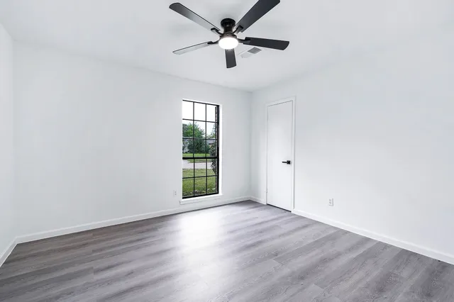 an empty room with wooden floor and windows