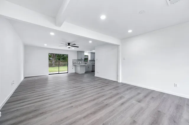 a view of empty room with wooden floor and windows