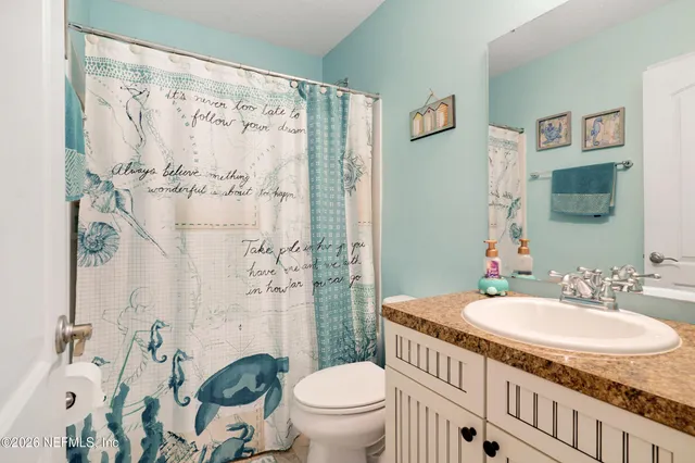 a bathroom with a granite countertop sink a toilet and a shower curtain