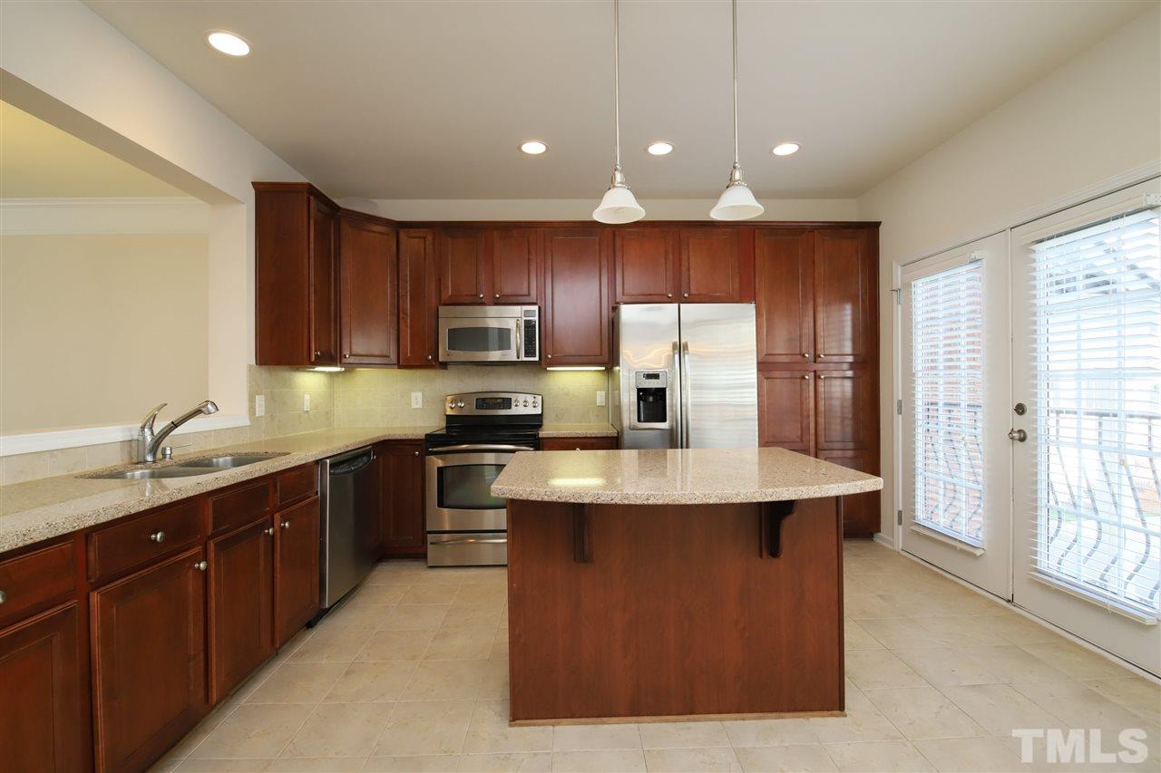 2619 Laurel Cherry Street Raleigh, NC 27612 - Photo 5 of 30 a kitchen with kitchen island granite countertop a sink stove refrigerator and cabinets