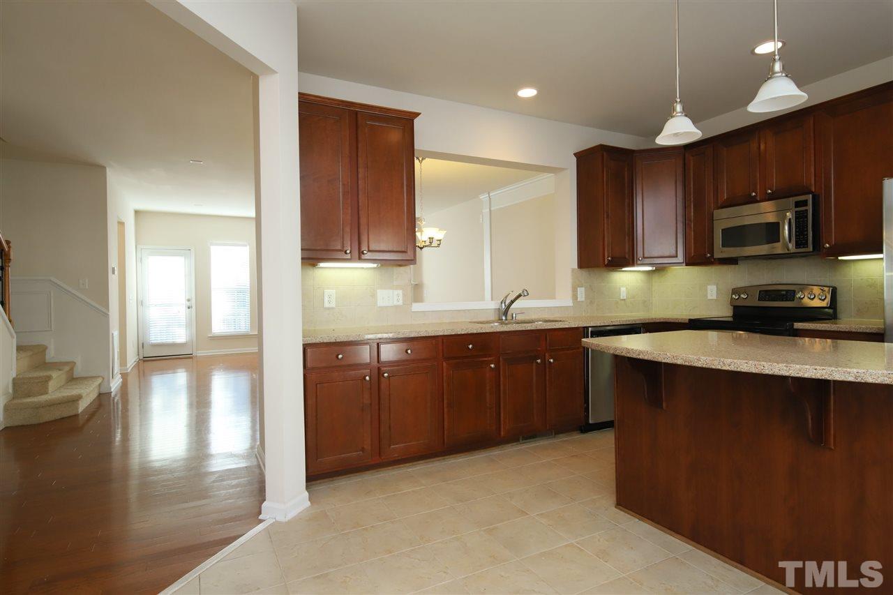 2619 Laurel Cherry Street Raleigh, NC 27612 - Photo 6 of 30 a kitchen with kitchen island granite countertop wooden cabinets a sink and a stove
