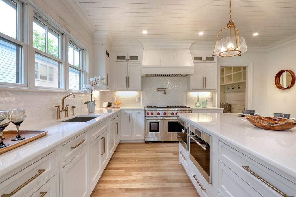 135 Waban Hill Road North Newton, MA 02467 - Photo 10 of 36 a large white kitchen with kitchen island a stove a sink a chimney wooden floor and cabinets
