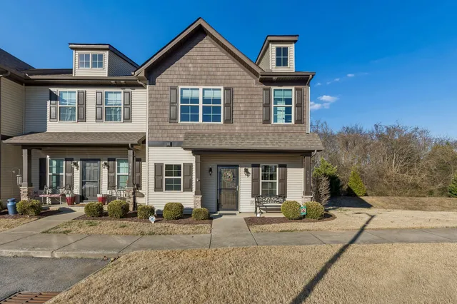 a view of a brick house with large windows and plants