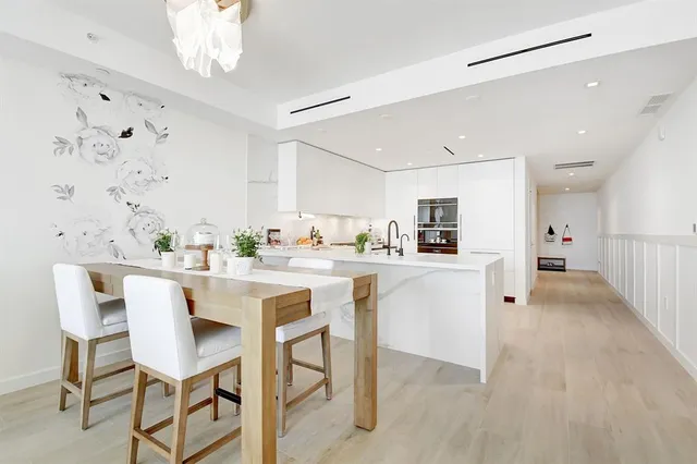 a kitchen with stainless steel appliances a dining table chairs and white cabinets