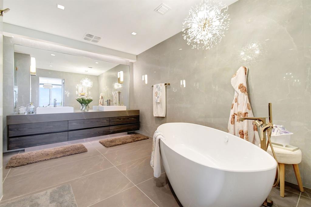 1116 North Ocean Boulevard, Unit 303 Pompano Beach, FL 33062 - Photo 21 of 52 a bathroom with a white tub a mirror and vanity