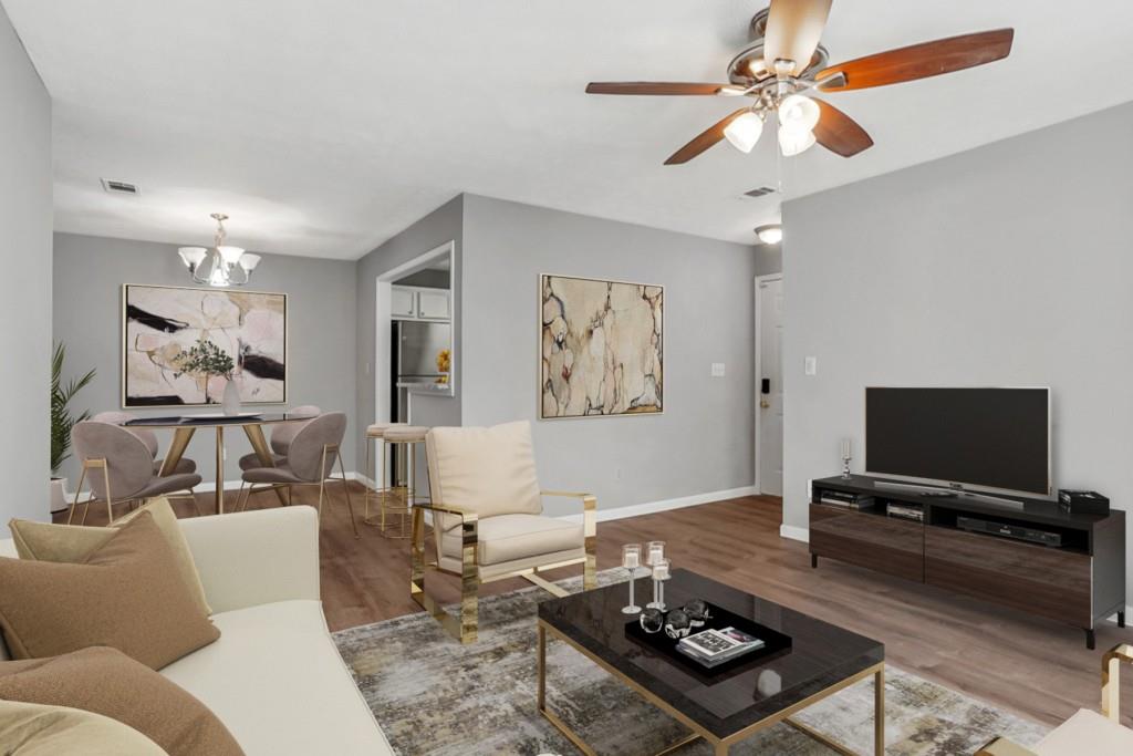 a living room with furniture a flat screen tv and a ceiling fan