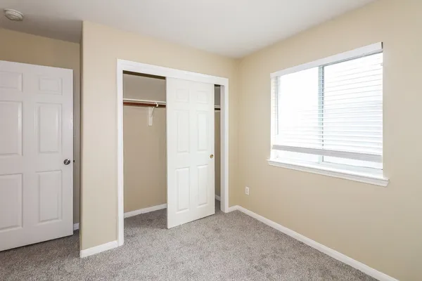 a view of an empty room with closet and a window