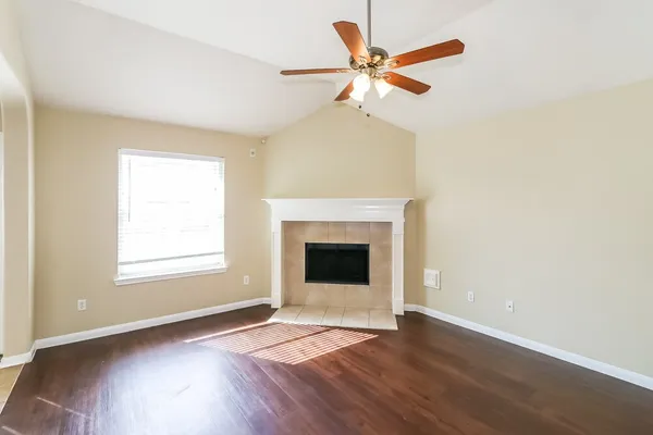 an empty room with wooden floor fireplace and windows