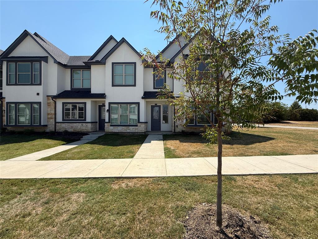 373 Buck Ridge Drive Frisco, TX 75068 - Photo 1 of 24 Modern townhome architecture featuring multiple gables, dark window trim, stone veneer accents, and a dark shingled roof