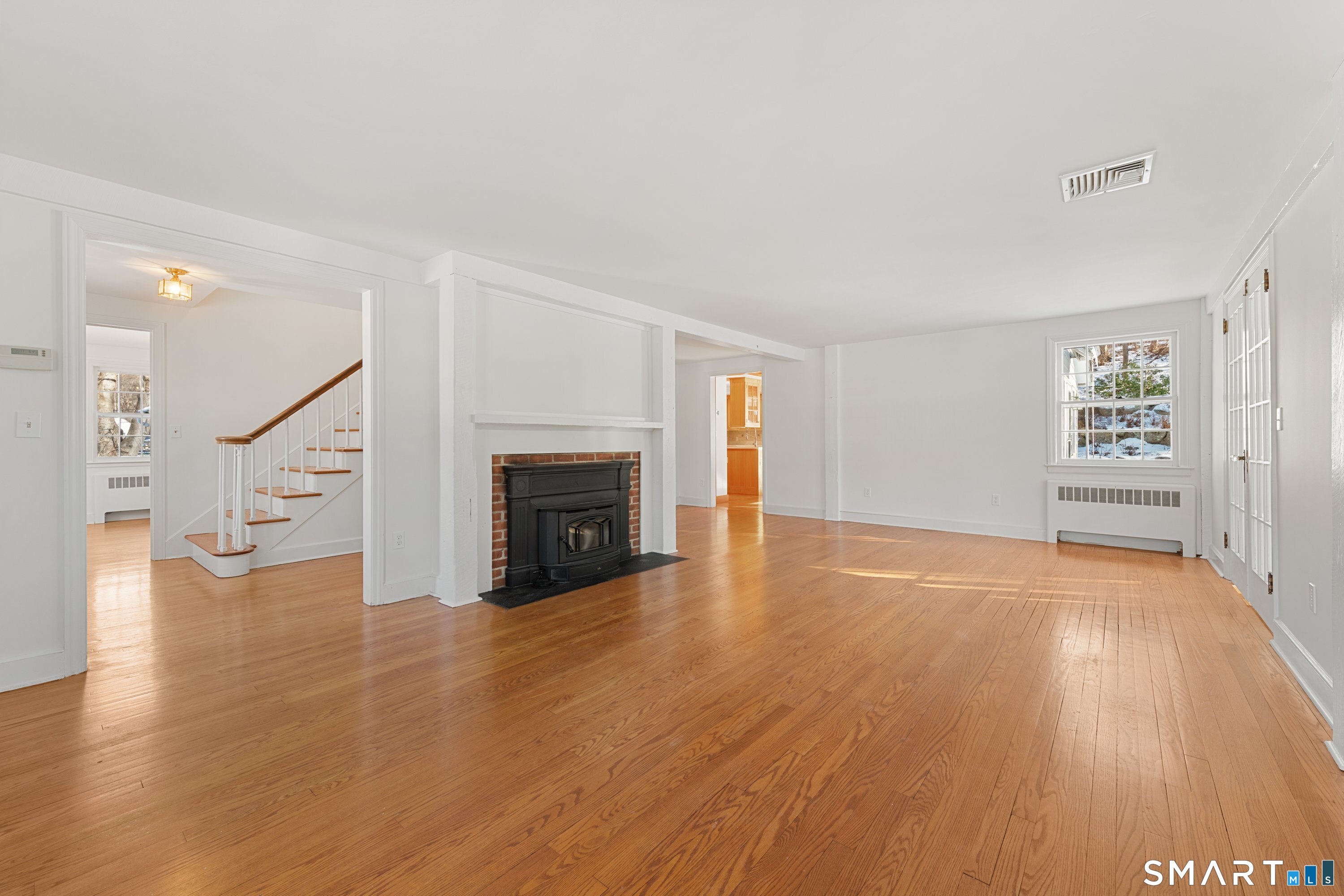 111 Lyons Plain Road Weston, CT 06883 - Photo 6 of 25 an empty room with wooden floor fireplace and windows