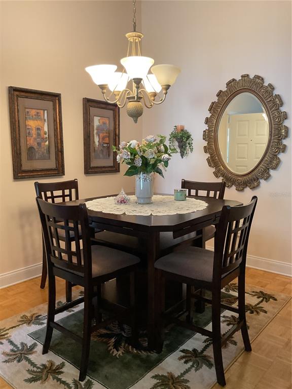 2655 Pine Ridge Way North, Unit D3 Palm Harbor, FL 34684 - Photo 9 of 31 a dining room with wooden floor a chandelier a wooden table and chairs