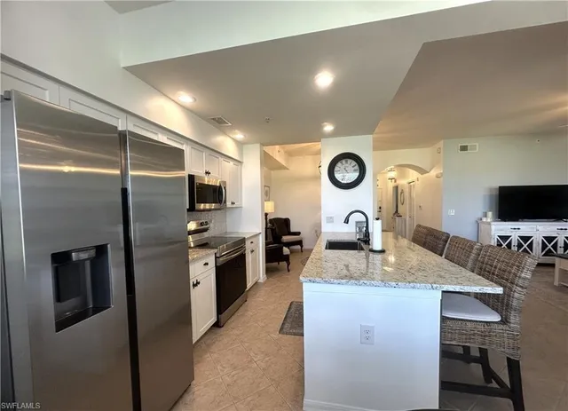 a kitchen with kitchen island granite countertop stainless steel appliances and a refrigerator