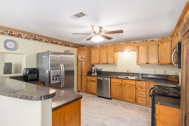 a kitchen with stainless steel appliances granite countertop a sink a stove and a refrigerator