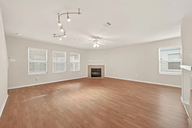 a view of an empty room with a window and wooden floor