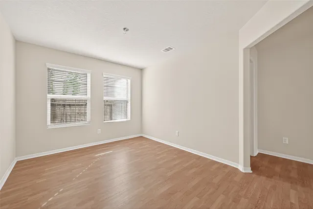 a view of an empty room with wooden floor and a window
