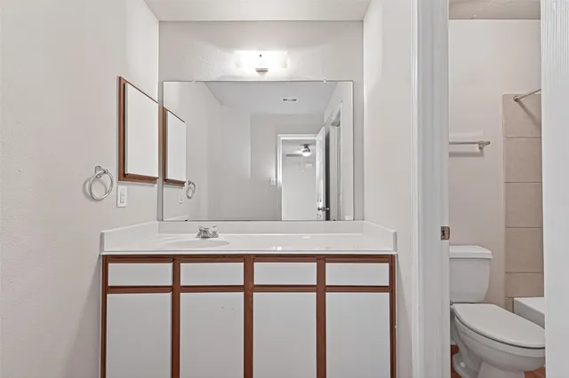 a bathroom with a granite countertop sink toilet and mirror