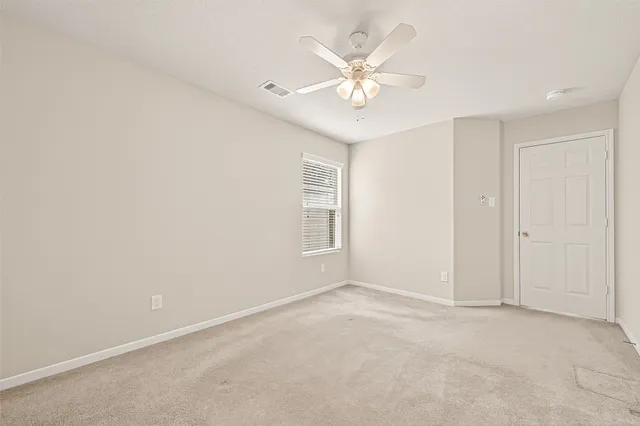 an empty room with a chandelier fan and windows