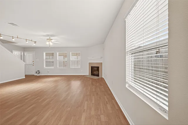 an empty room with wooden floor and windows