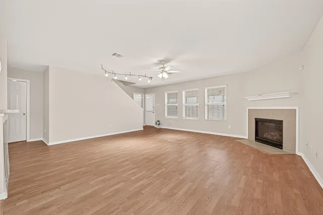 an empty room with wooden floor fireplace and windows
