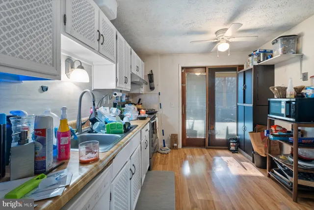 a kitchen with stainless steel appliances granite countertop a sink dishwasher a refrigerator and white cabinets with wooden floor