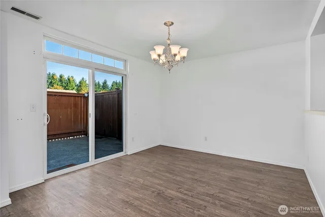 a view of an empty room with wooden floor fireplace and a window