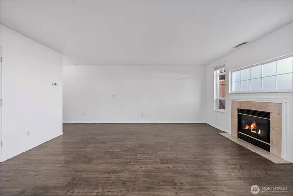 an empty room with wooden floor fireplace and windows